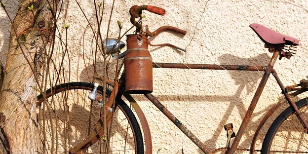 Egy régi, rozsdás tejesdoboz lóg a kerékpár kormányán